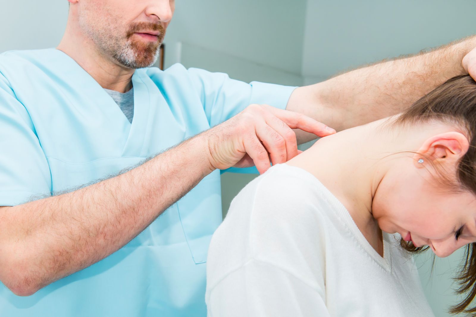 Image of a Physical Therapist examining a patient's cervical vertebrae.